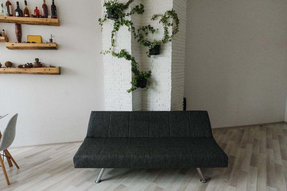 Contemporary living room with dark grey sofa and decorative wall plants on white brick.